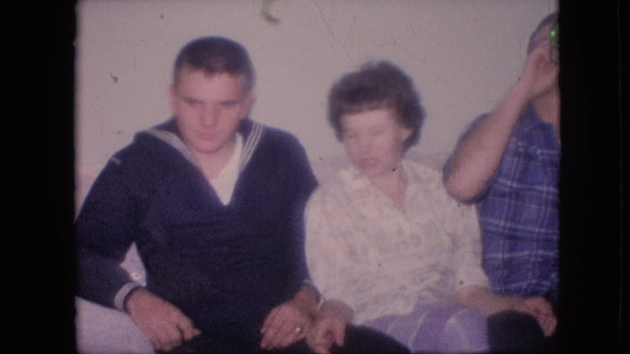 Adults seated together on a couch, with a man in a sailor-style sweater beside a woman.