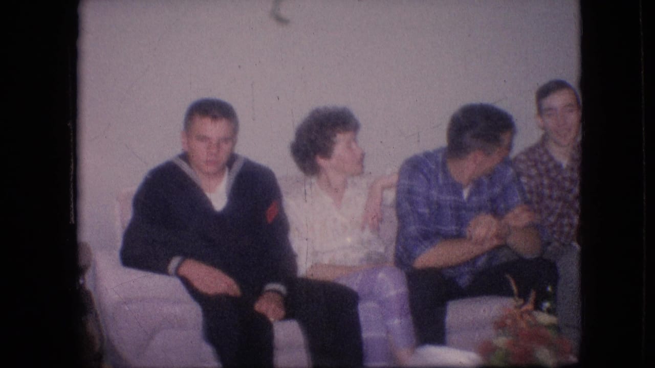 Adults on a couch, with one woman turned toward a man in a blue plaid shirt.