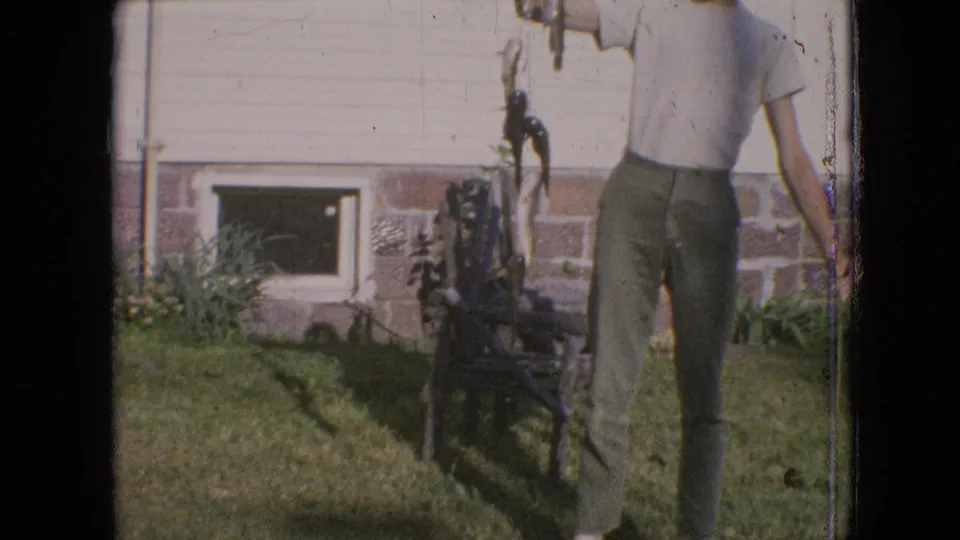 The final frame crops the man partly at the head and side while the fish line, grassy yard, house foundation, small window, and yard chair or frame remain visible.