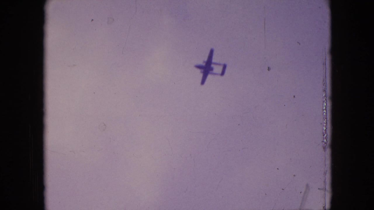 Small aircraft silhouette near the upper part of a pale sky frame.