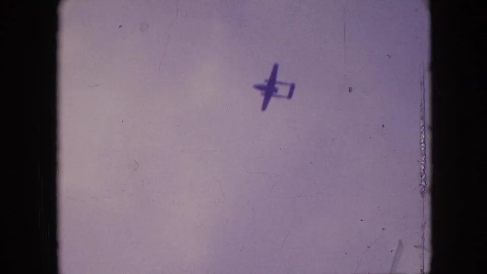 Small plane silhouette high in the frame against a pale sky, supported by supplied 1964 Philadelphia clip metadata.