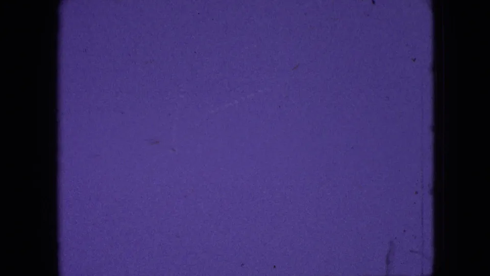 Purple-tinted 8mm frame from the 1964 Philadelphia-area clip with film edges, dust, and minimal visible scene detail before the hillside view appears.