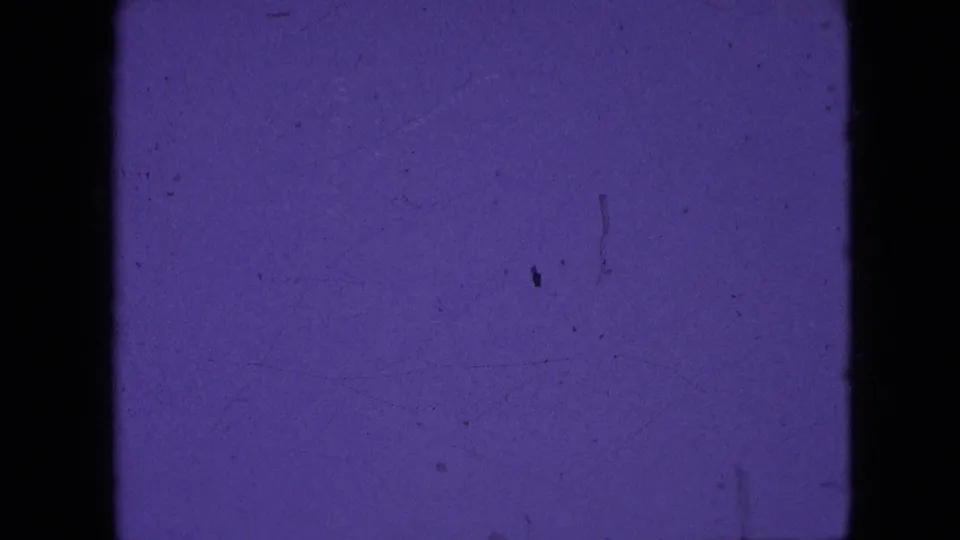 A second purple-toned 8mm frame from the 1964 Philadelphia-area footage, showing mostly film texture, dark borders, and faint dust without clear landscape detail.