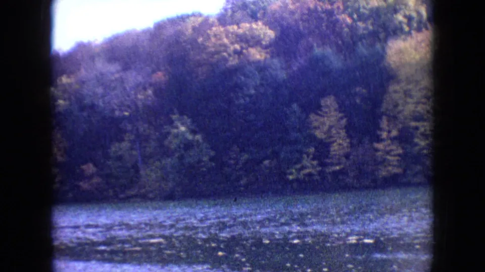 The final 1964 Philadelphia frame looks across the lake toward wooded autumn hills, with blue-purple 8mm color shift and dark frame edges.