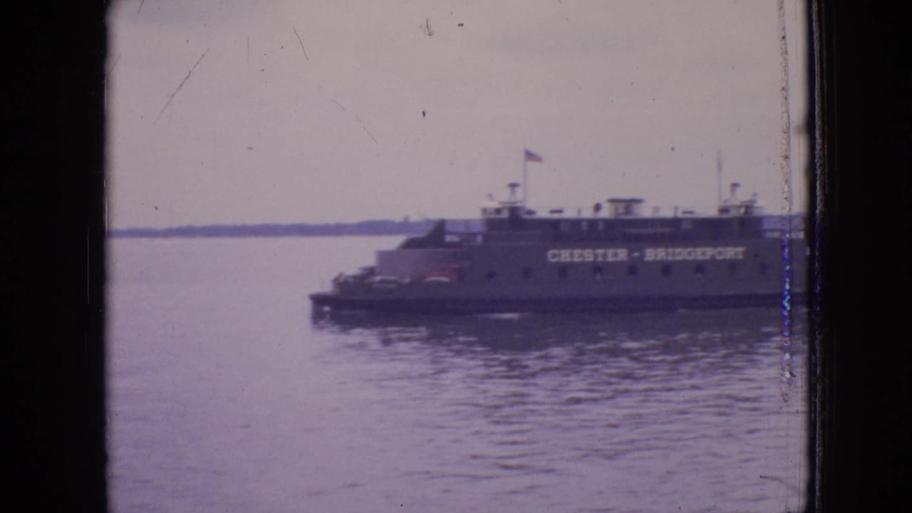 The Chester-Bridgeport ferry appears farther right in the frame, filmed across rippled water with muted 8mm color and visible gate edges.