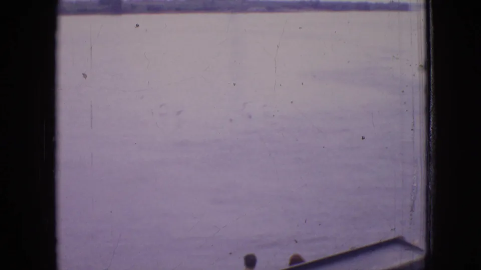 Wide 8mm view across a calm Philadelphia-area waterway, with the far shore near the horizon and a sliver of boat structure at the lower edge.