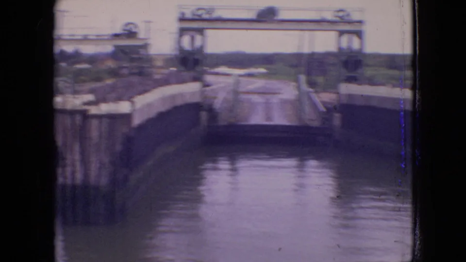 1964 Philadelphia-area 8mm footage shows lock gates, water, lock walls, and distant shoreline from a vessel-level viewpoint.