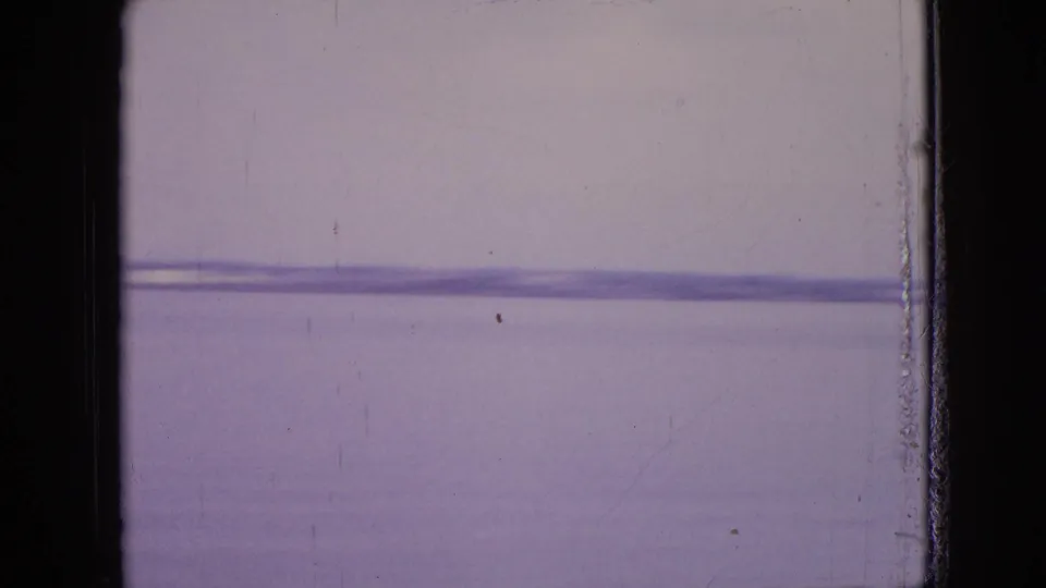 A soft 8mm frame from the end of the lock sequence shows a pale surface with faint horizontal bands, scratches, and edge wear rather than distinct subject detail.