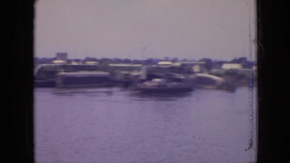 A wider Philadelphia harbor view shows a ferry-like vessel near dockside structures with water in the foreground, softened by motion blur and 8mm film grain.