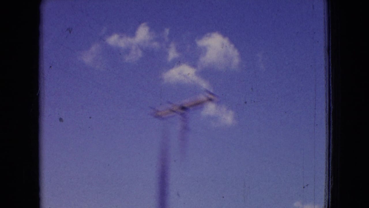 1965 New Jersey 8mm frame showing blue sky, small white clouds, and a utility pole passing quickly beside the road.