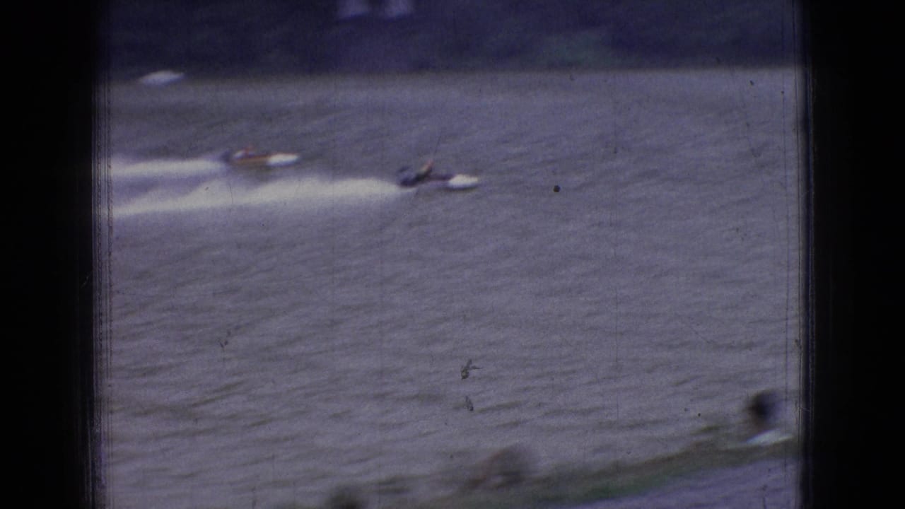 Several distant motorboats appear on a broad river during a 1965 New Jersey powerboat race, with white wake trails behind them.
