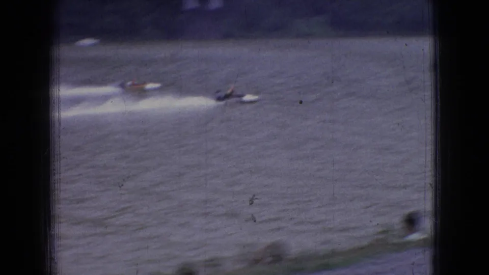 Several distant motorboats appear on a broad river during a 1965 New Jersey powerboat race, with white wake trails behind them.