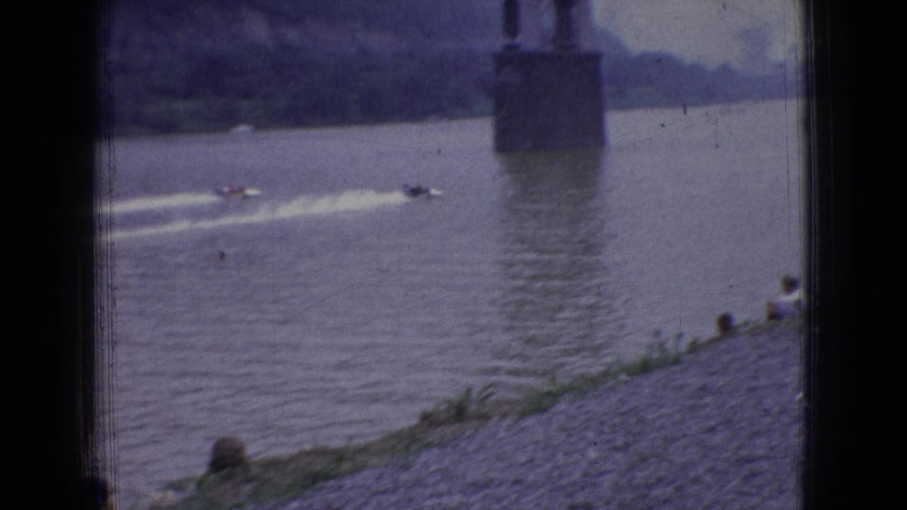 Powerboats pass near a large bridge pier or vertical structure on a river.