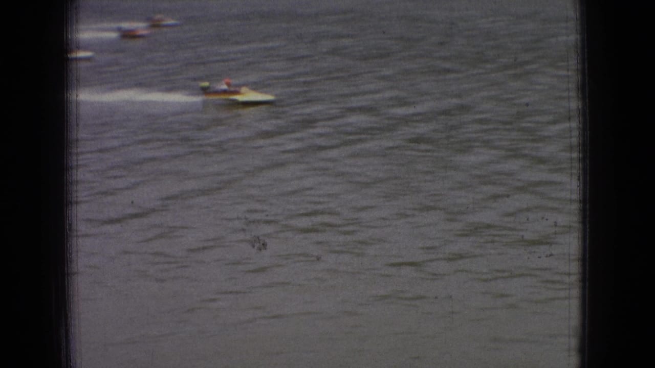 A small open motorboat speeds over the river in the foreground while other boats appear in the distance in this 1965 New Jersey 8mm frame.