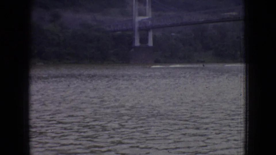 The final frame shows a small boat or wake on a New Jersey lake in 1965, with a distant bridge-like structure and wooded shoreline behind dark foreground framing.