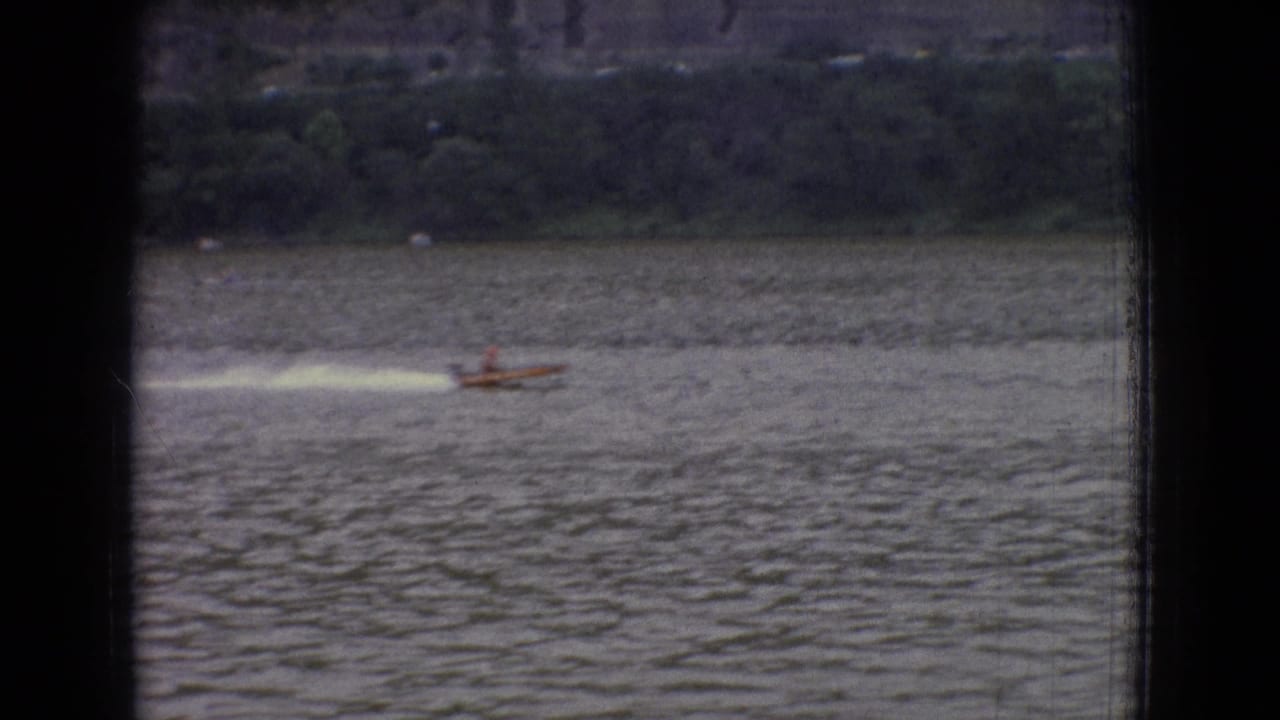 Speedboat throwing a white wake across rippled water.