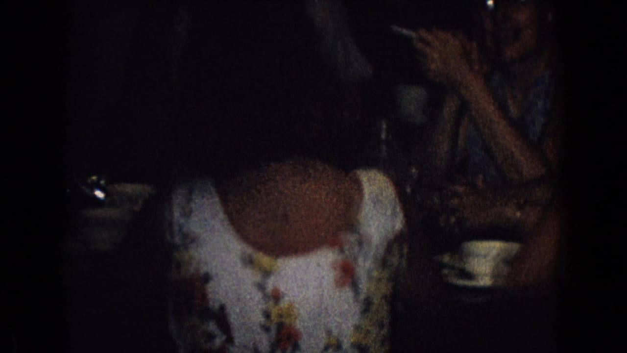 Woman in a floral dress seated at a table with a cup and saucer.