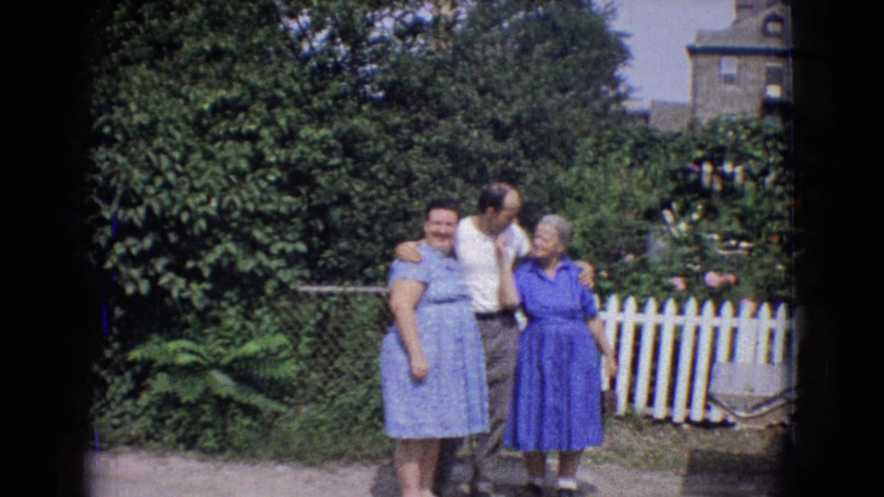 Three adults remain grouped near a fence, with the man turned toward the older woman.