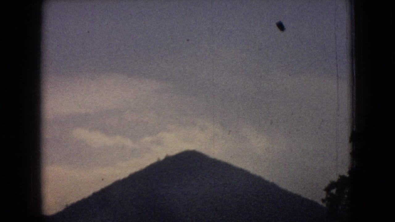 Sloping dark hill beneath a cloudy blue-gray sky.