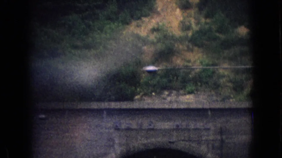 End frame of the 1965 8mm clip showing a dark tunnel or bridge face, wooded hillside, roadside lamp, and soft home-movie exposure near the Sideling Hill approach.