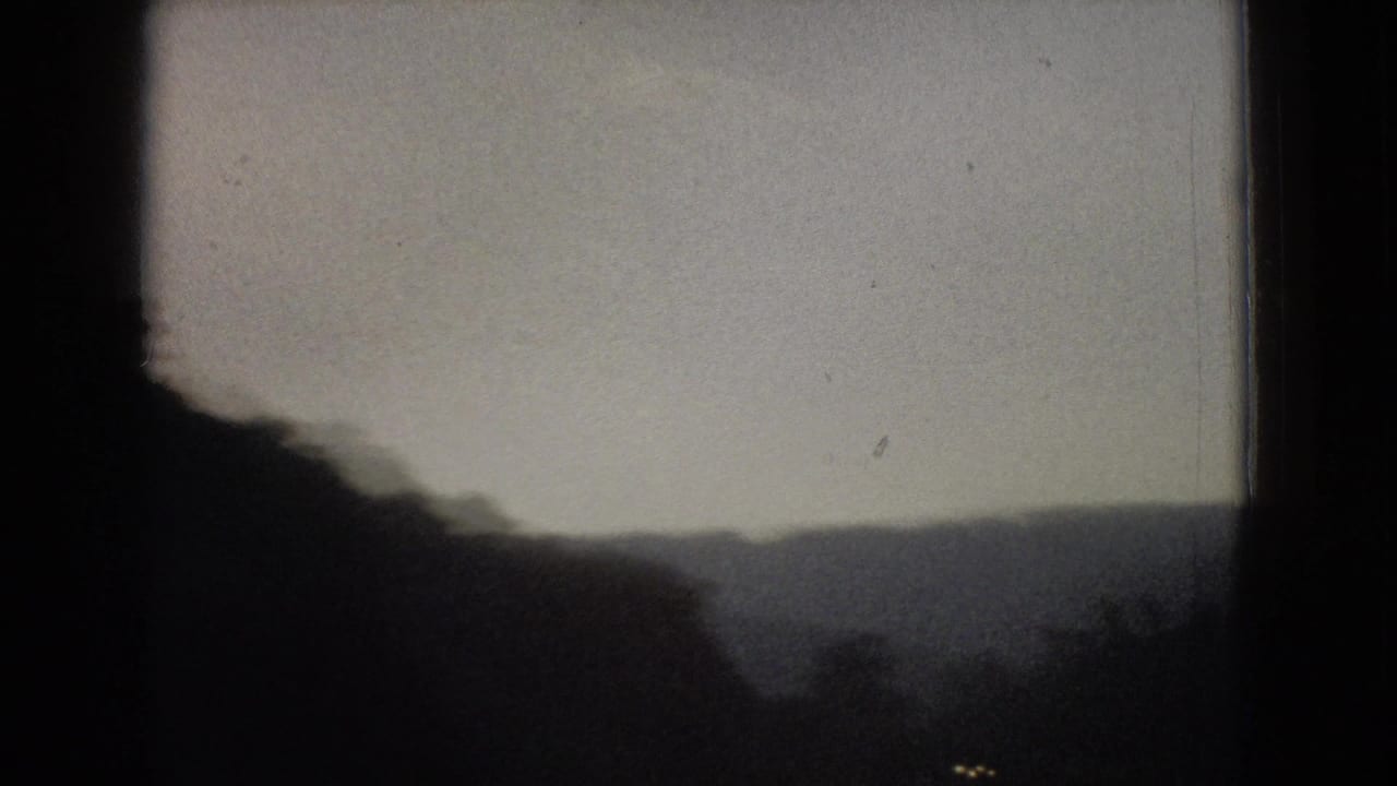 Forested ridge and distant hills partly obscured by a dark vertical window edge.