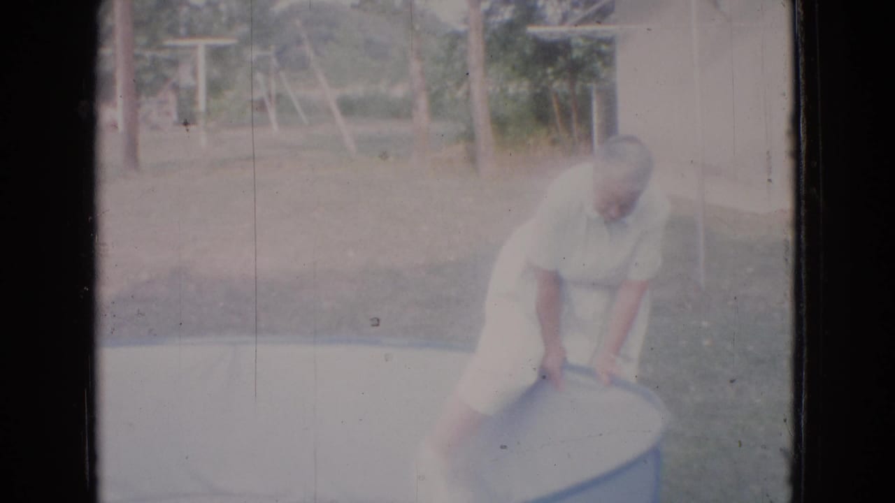Older woman bends over the edge of an empty above-ground pool outdoors.