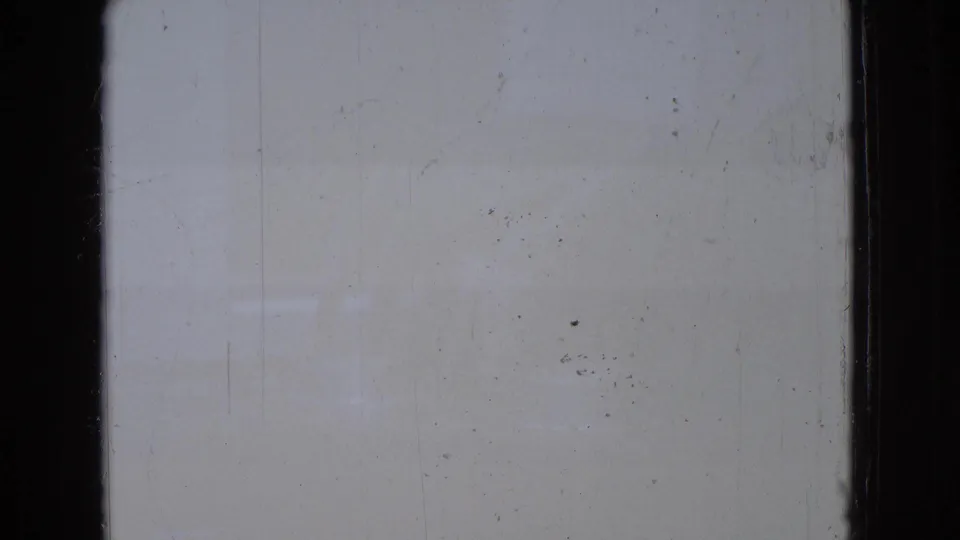 A mostly blank 8mm frame from the 1965 New Jersey clip shows pale exposure, surface marks, dust, and black film-gate edges before the zoo animal shots begin.
