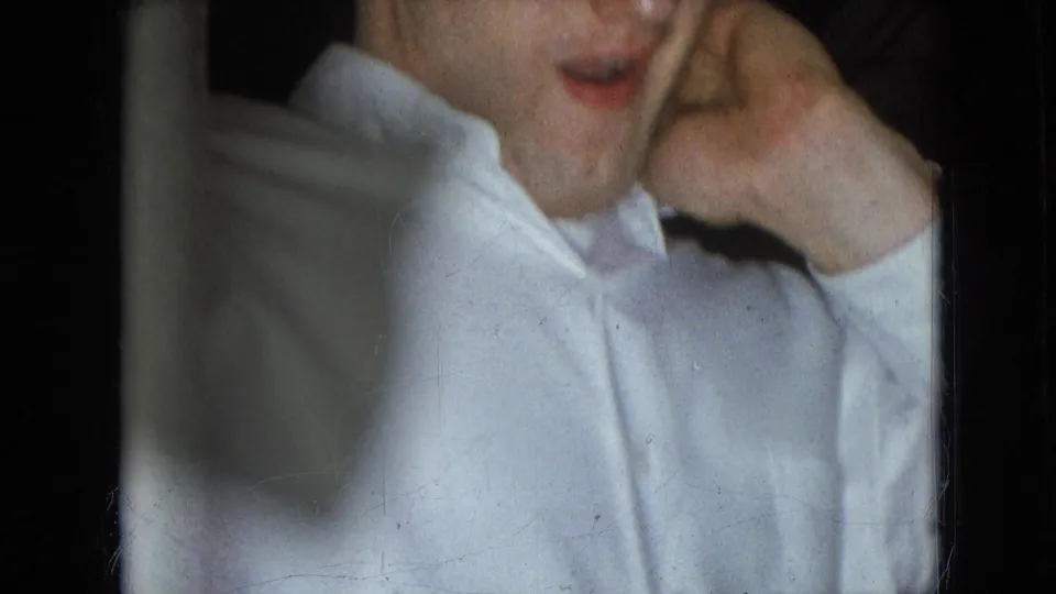 Athens, Ohio 1966 home-movie frame with a partially visible adult man in a white dress shirt standing near dark interior framing.