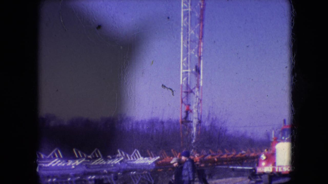 Communication tower work site with a service truck and a worker near stacked metal sections.