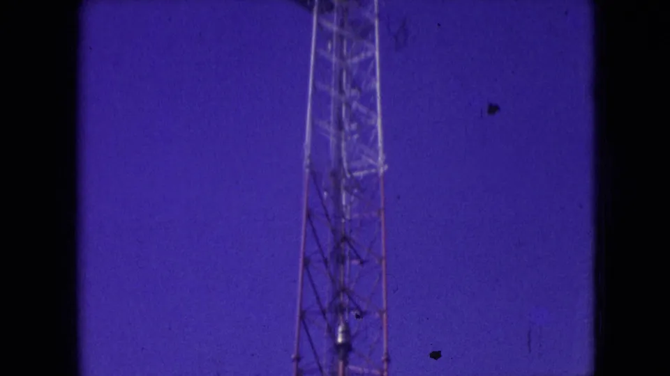 Athens, Ohio 1966 frame showing the upper portion of a metal communication tower with film scratches, dust, and dark gate edges.