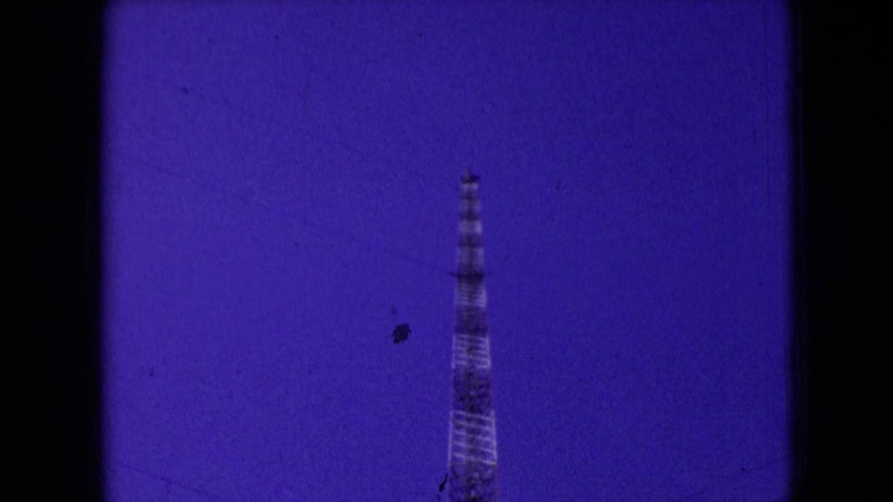 A tall lattice-like tower stands against a deep purple sky in 1966 Athens, Ohio home-movie footage, with heavy film tint and dark frame borders.