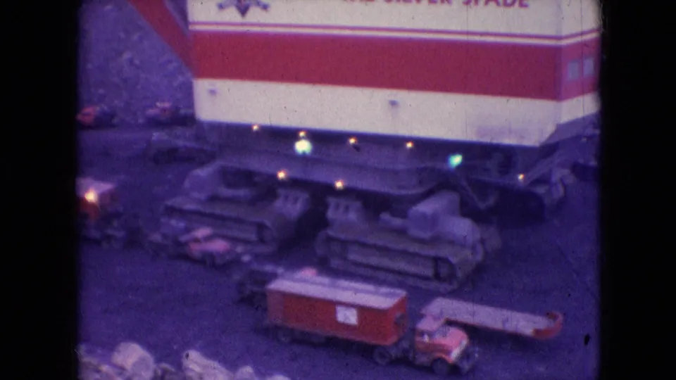 1966 Athens, Ohio home-movie frame showing a large tracked machine with red-and-white body panels, small work lights, and partially readable lettering near a roadside or work area.