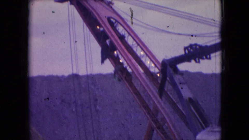 1966 8mm frame from Athens, Ohio focused on the Silver Spade boom, cables, and a portion of the machinery against the surface mine background.