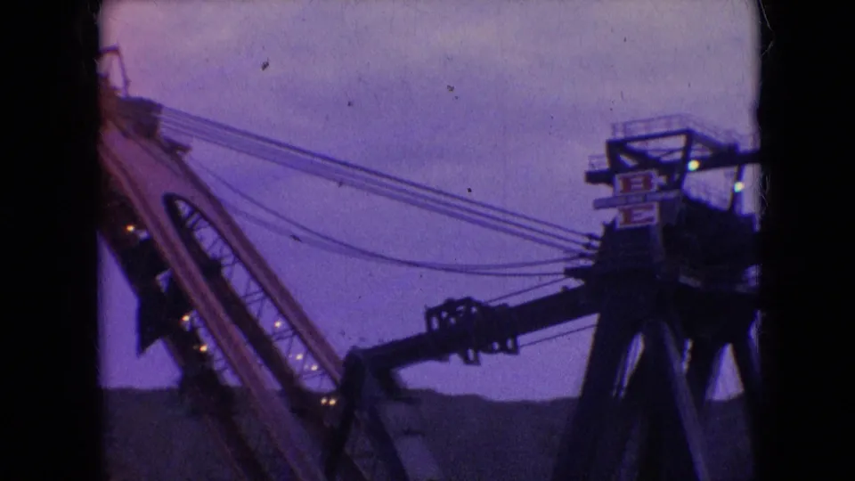 1966 Athens, Ohio 8mm frame showing an angled crane boom and cables leading to a dark machinery head with small illuminated points and possible brand markings.