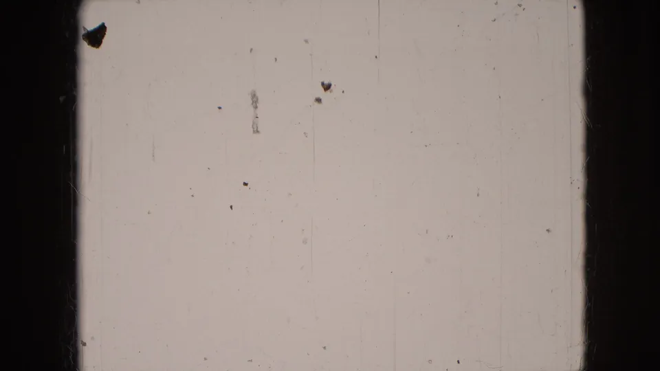 Blank or leader-like 8mm frame with dust, scratches, pale emulsion tone, and dark vertical film borders.