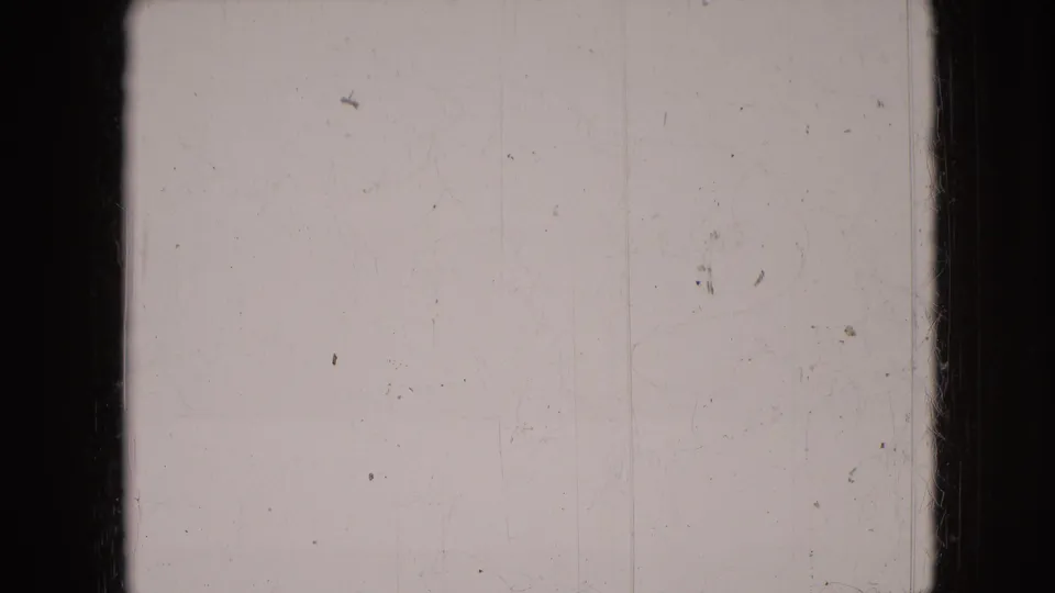 Aged 8mm frame showing mostly blank exposed film, visible dust, scratches, and a dark vertical divider from the contact sheet layout.