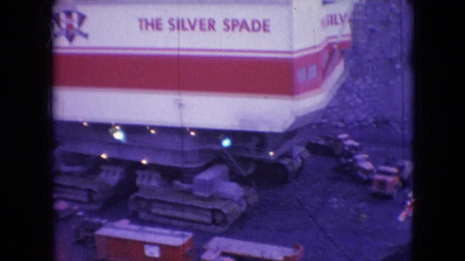 1966 Athens, Ohio 8mm frame showing the red-and-white side of The Silver Spade excavator above a tracked undercarriage, with visible lettering and aged color film texture.