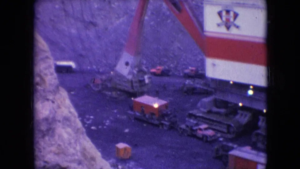 Wider 1966 Athens, Ohio 8mm view of the Silver Spade mining machine in an open pit, with its tracked base, service vehicles, and steep exposed mine walls.