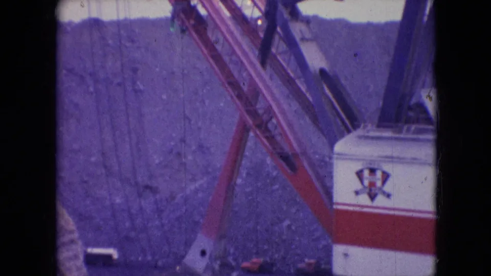 1966 Athens, Ohio frame focusing on the Silver Spade machine's boom and bucket area beside a steep open-pit wall, with the branded machine body partly visible.