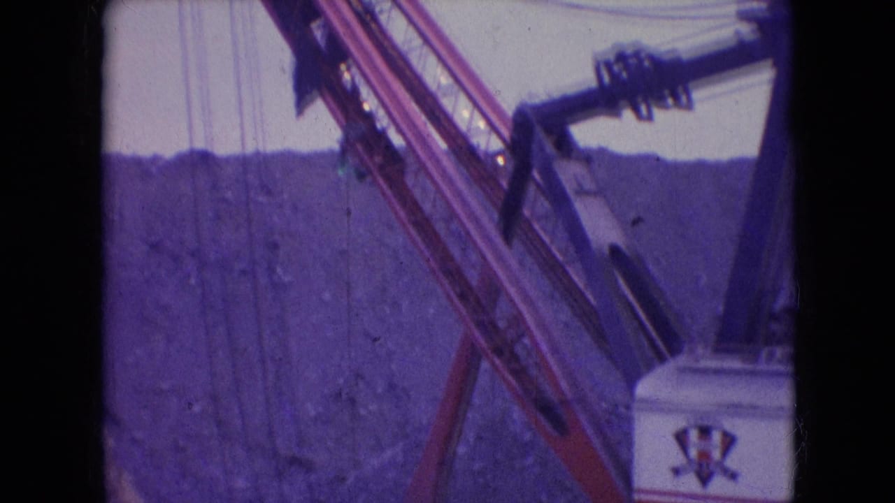 1966 Athens, Ohio 8mm frame showing a large quarry excavator with lattice boom, cables, and partial machine housing in front of a rocky slope.