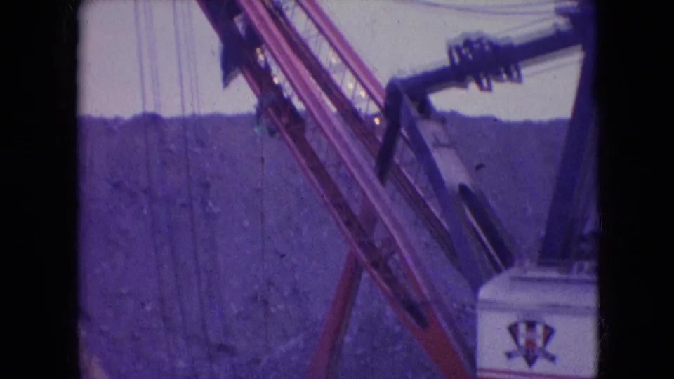 1966 Athens, Ohio 8mm frame showing a large quarry excavator with lattice boom, cables, and partial machine housing in front of a rocky slope.