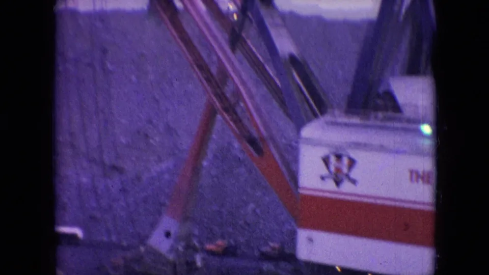 1966 Athens, Ohio 8mm frame showing the excavator body, angled boom, cables, and rocky quarry face from a close home-movie vantage.