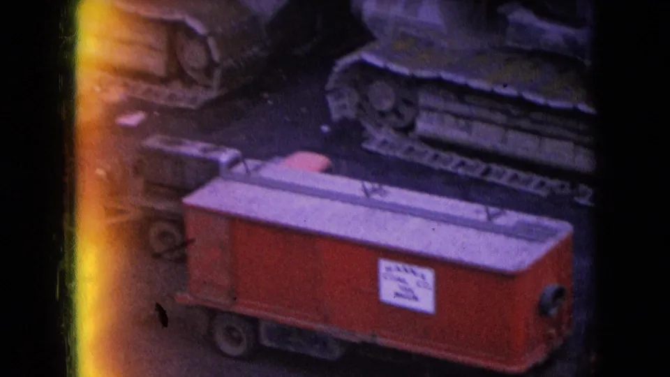 1966 Athens, Ohio home-movie frame showing a red labeled railcar passing in front of heavy crawler-mounted mining equipment at a mine site.