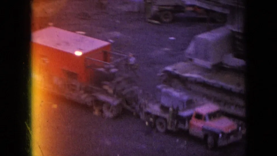 1966 Athens, Ohio frame showing a mine yard with a red coal railcar, large tracked machinery, and small service vehicles under strong 8mm light leaks.