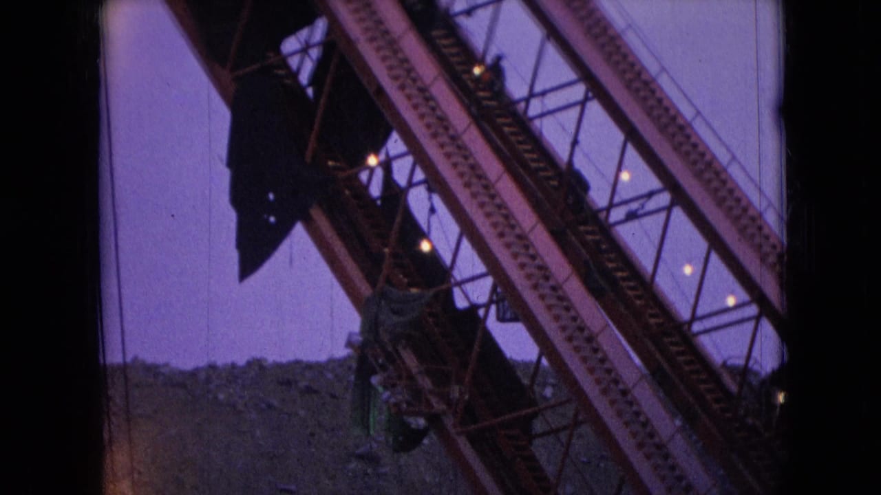 1966 Athens, Ohio 8mm frame showing a diagonal steel crane boom with cables and dark structural details silhouetted against a purple twilight sky.