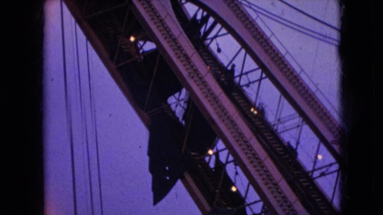 1966 Athens, Ohio 8mm frame with a close upward view of crane girders, cable lines, and dark pulley hardware set against the twilight sky.