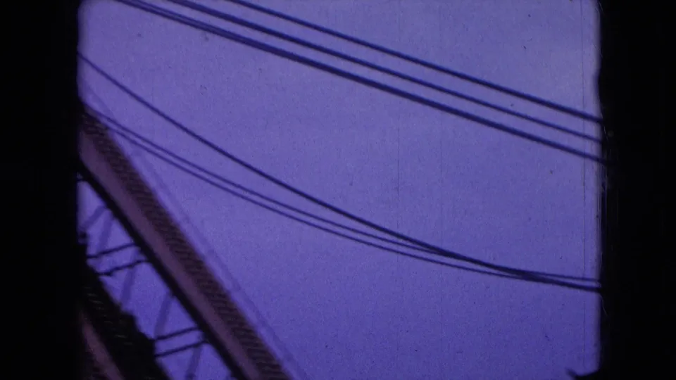 1966 Athens, Ohio frame with a diagonal crane or boom structure crossing the right side while multiple electrical wires stretch across a purple night sky.