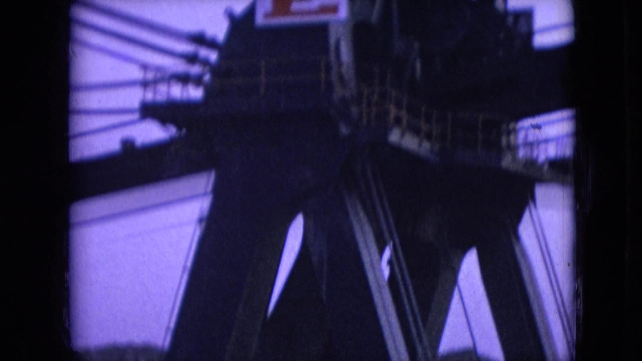 1966 8mm footage from Athens, Ohio showing dark industrial machinery, beams, and railings in low light with a purple film cast.