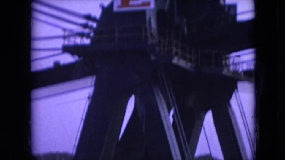 1966 8mm footage from Athens, Ohio showing dark industrial machinery, beams, and railings in low light with a purple film cast.