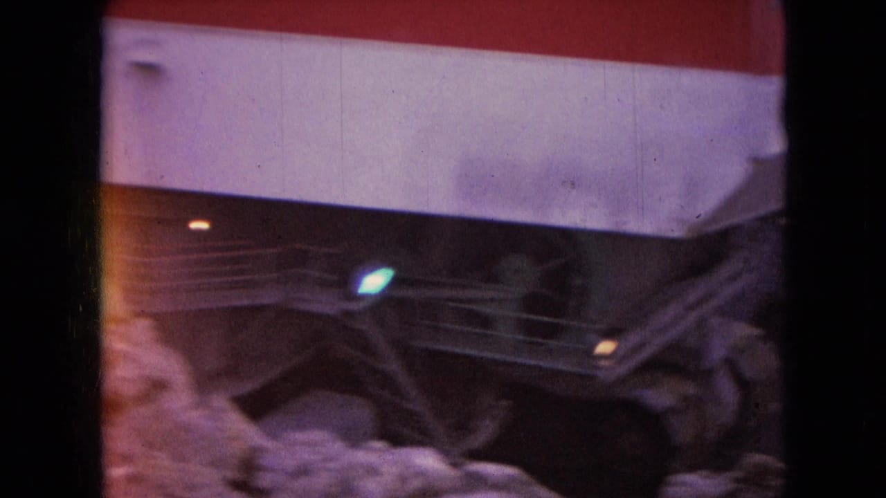 1966 Athens, Ohio 8mm frame showing a red and white striped industrial structure, shadowed metal or structural elements, and snow piled in the foreground.